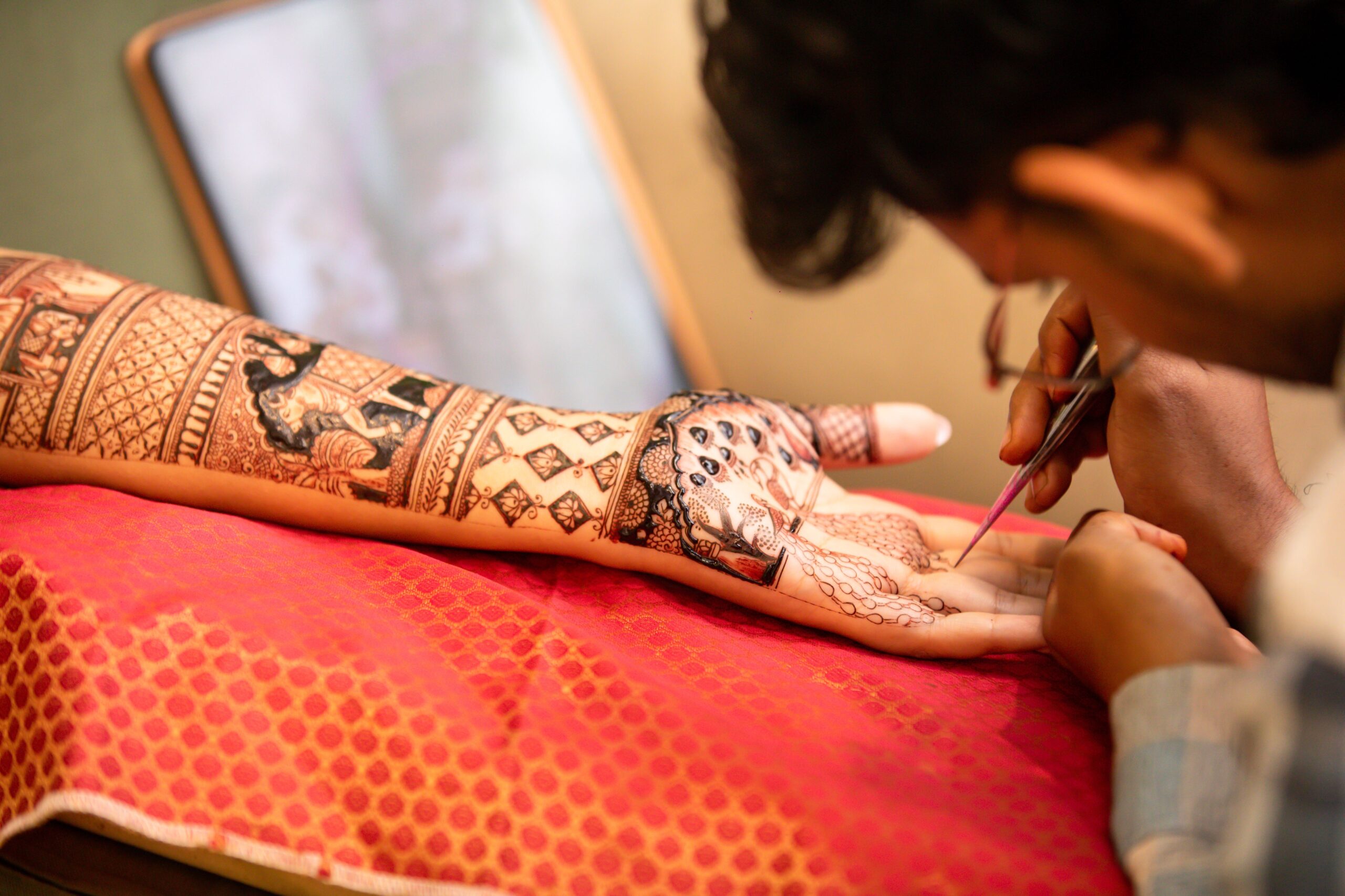 A person applying intricate henna design on an arm, showcasing artistic detail.